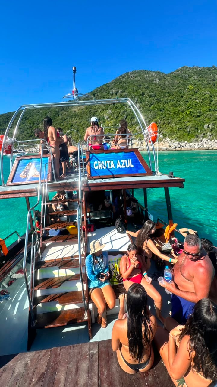 Passageiros relaxando no deck da Gruta Azul com cooler e piso decorado com orca