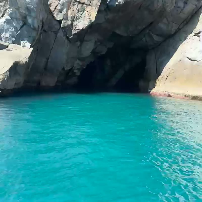 Embarcação passando por formação de pedras no mar de Arraial do Cabo
